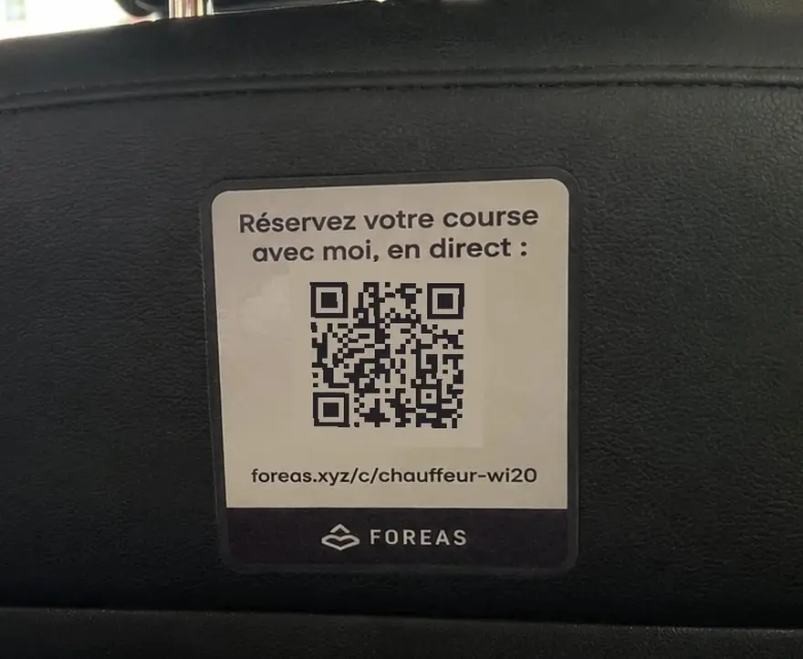 Autocollant FOREAS au dos d’un siège : « Réservez votre course avec moi, en direct », avec un code à scanner.